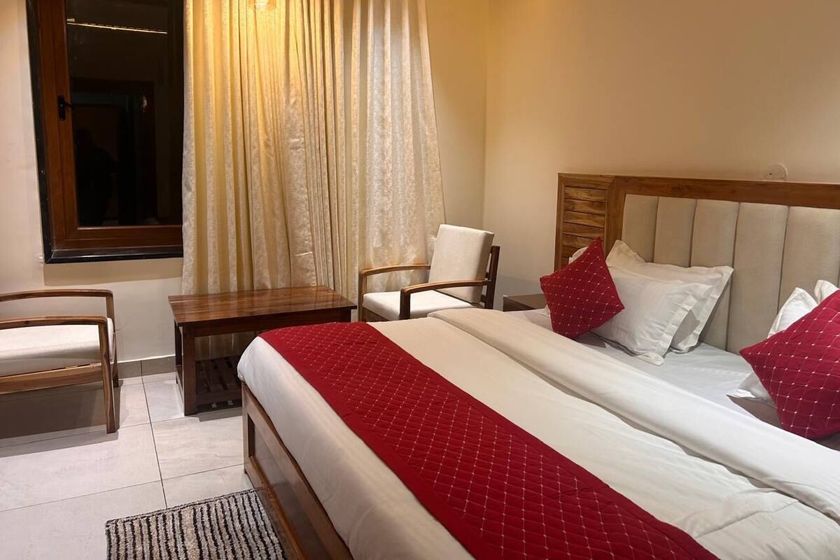 Een hotelkamer met een bed, een stoel, een tafeltje en een raam met gordijnen.