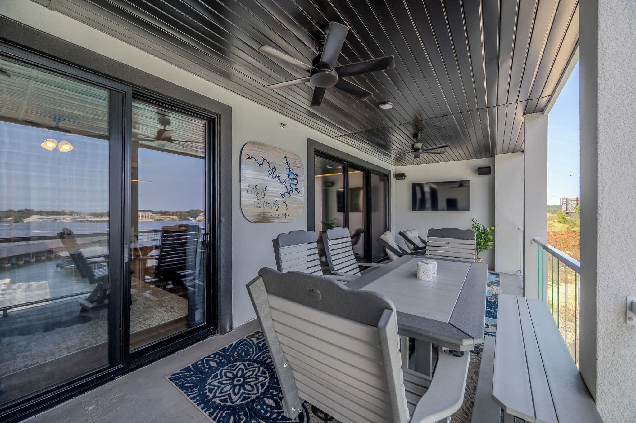 A covered outdoor dining area with a table and chairs, a ceiling fan, and a view of the cityscape.
