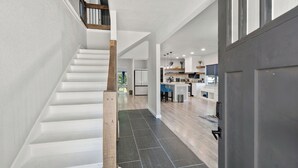 A modern kitchen with white cabinets, a central island, and a view into the dining area. - Gorgeous 6BR Sleeps 16 with Hot Tub, BBQ, Games, Big Screen TV.  Near Downtown (San Antonio)