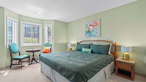 A bedroom with a bed, two chairs, a small table, a nightstand, and a window. - Have It All Stay Central, Swim Often (Osage Beach)