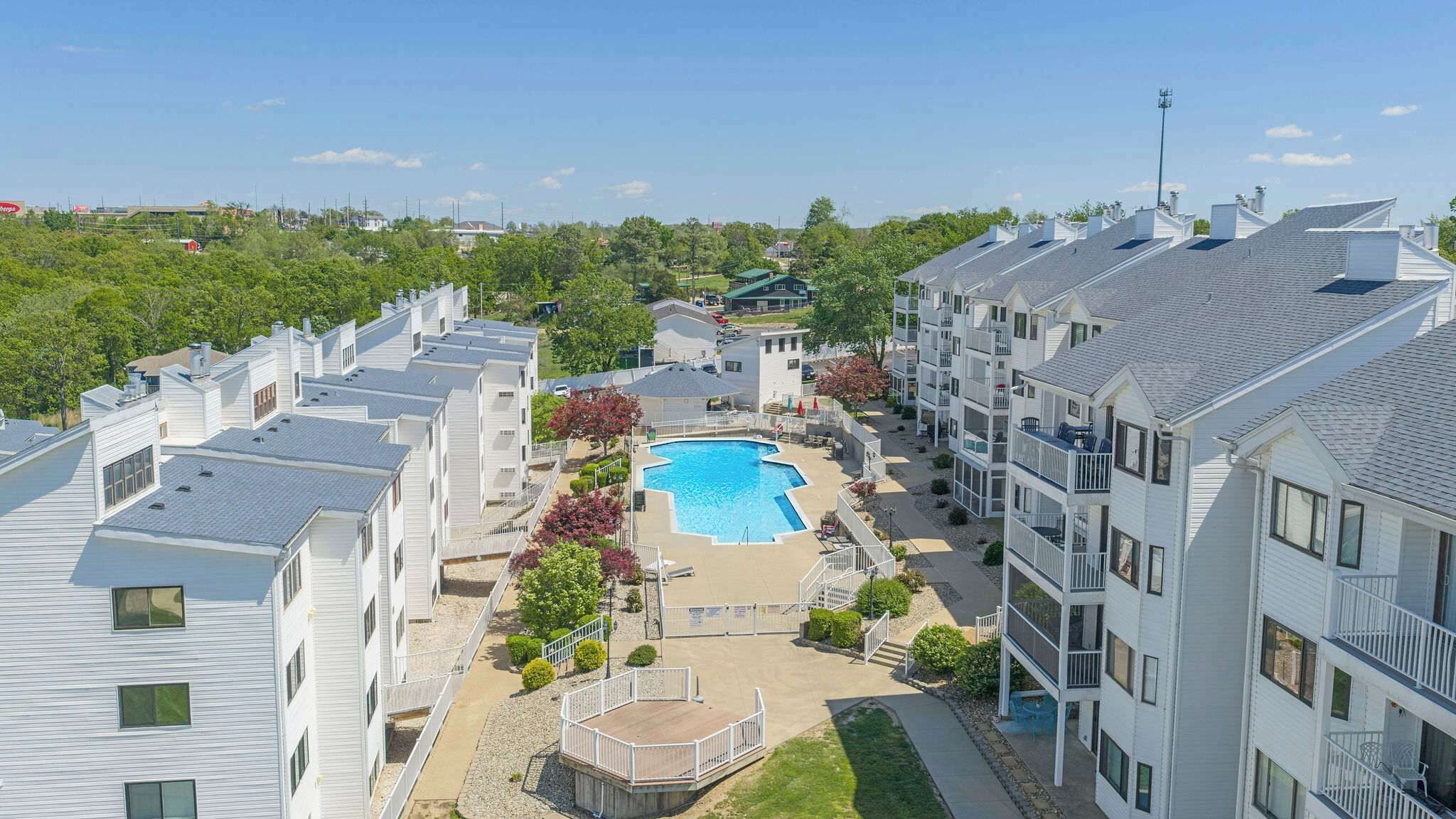 Un immeuble résidentiel doté d’une piscine, de nombreux balcons et offrant une vue dégagée sur les environs.