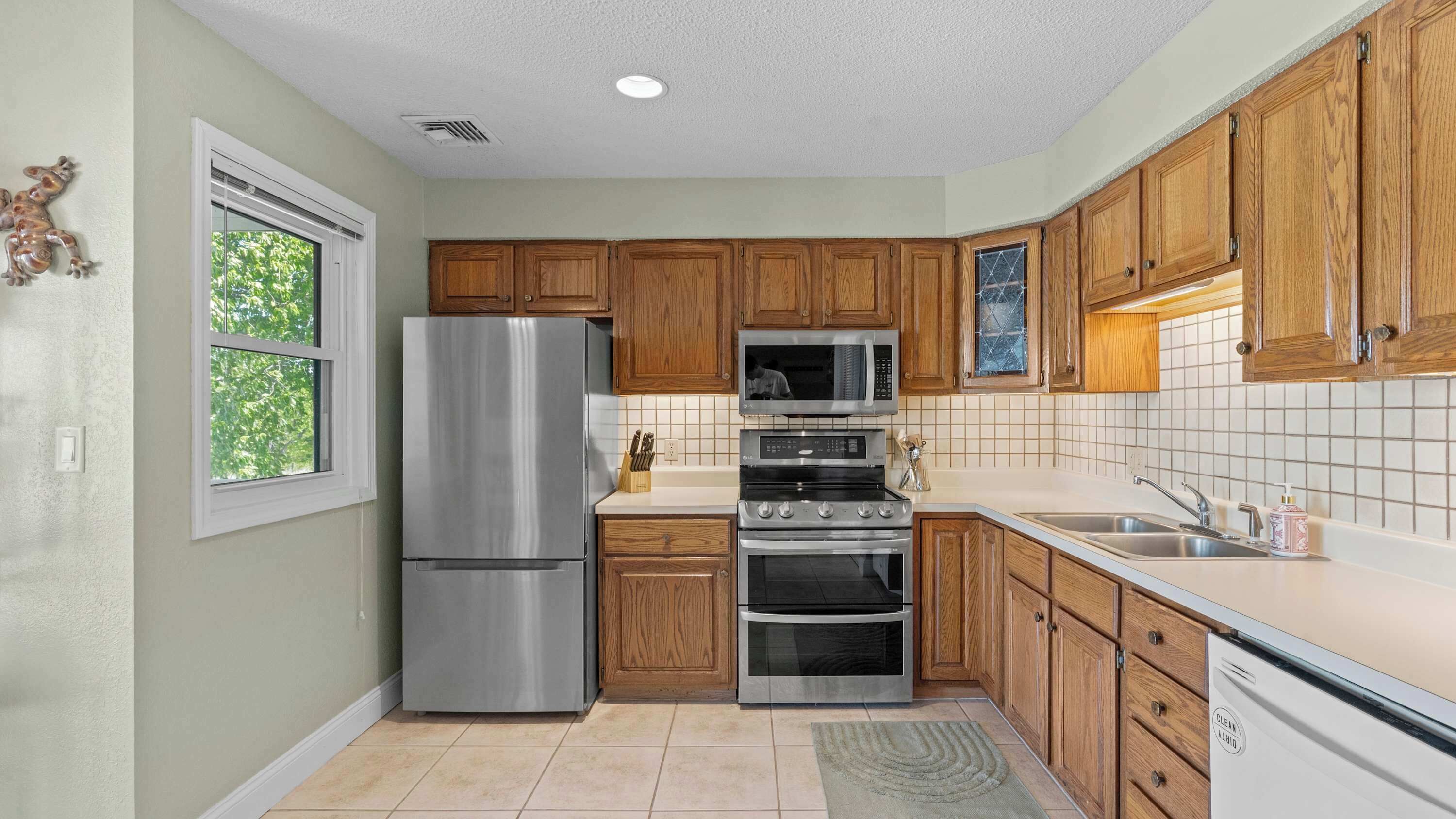 A kitchen with wooden cabinets, a stainless steel refrigerator, a microwave, an oven, and a dishwasher.