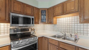 A kitchen with wooden cabinets, a microwave, an oven, and a sink. - Have It All Stay Central, Swim Often (Osage Beach)