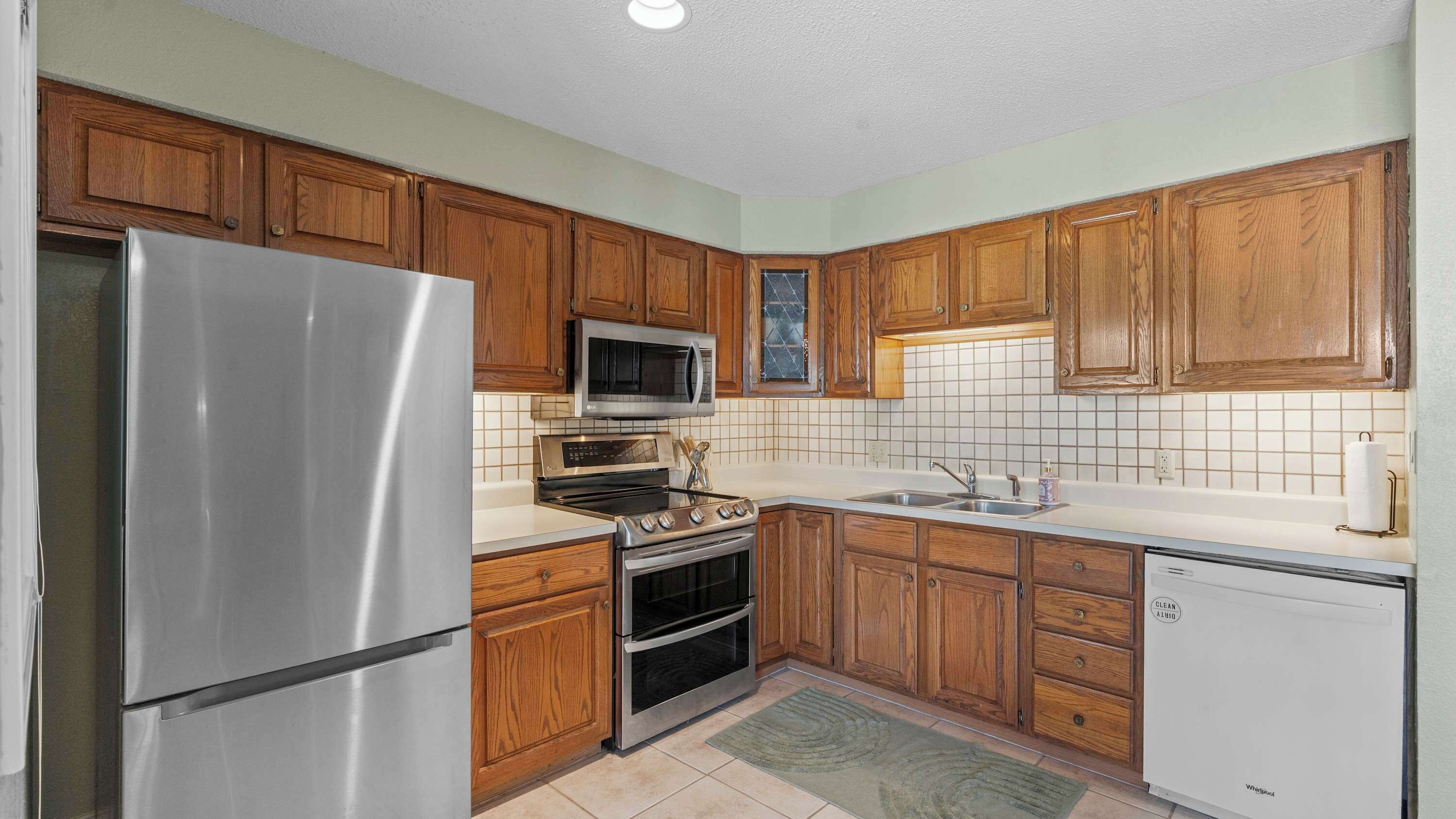 A kitchen with wooden cabinets, stainless steel appliances, a microwave, oven, and a dishwasher.