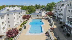 A residential building with a central swimming pool, surrounded by balconies and a landscaped garden. - Have It All Stay Central, Swim Often (Osage Beach)
