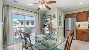 A dining area with a glass table and chairs, a ceiling fan, kitchen cabinets, and a view of the outside. - Have It All Stay Central, Swim Often (Osage Beach)