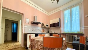 Una cocina compacta con zona de comedor, un radiador y una ventana con cortinas.