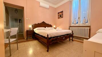 A bedroom with a wooden bed, bedside lamps, a radiator, and a window with curtains.