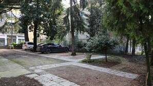 Un camino pavimentado, coches aparcados y árboles en una zona residencial.