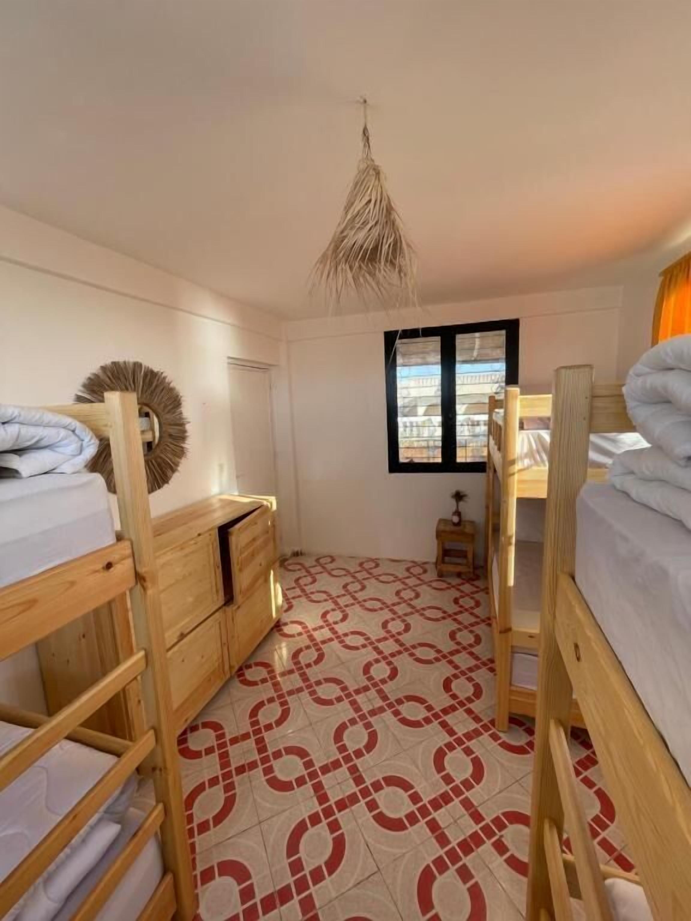 Un dormitorio con literas, un aparador de madera y piso estampado.