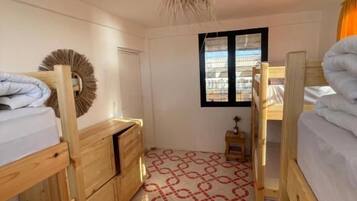 Un dormitorio con literas, un aparador de madera y piso estampado.