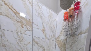 A shower area with marble tiles and a metal rack holding toiletries.