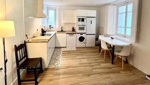Une cuisine moderne avec des meubles blancs, un four encastré et un lave-linge.