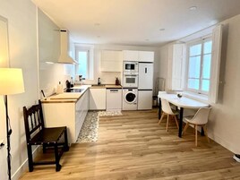 Cocina moderna con armarios blancos, horno empotrado y lavadora.