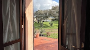 Une pièce dotée d’une porte-fenêtre coulissante qui donne sur un patio extérieur, avec un sol carrelé et des plantes en pot.
