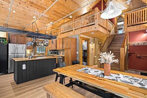 Eine geräumige Küche mit Holzschränken, einer großen Kochinsel und einem Essbereich mit Tisch und Bänken.