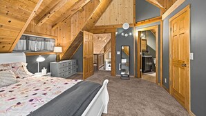 Une chambre avec un plafond en pente, un lit, une commode et un miroir.