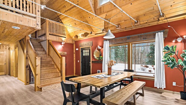 Un intérieur en bois comprenant une table à manger, des chaises, un banc et un escalier.