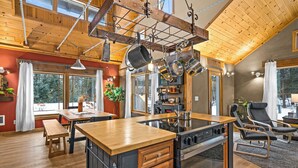 Une cuisine spacieuse avec des meubles en bois, un îlot central et des ustensiles de cuisine suspendus.