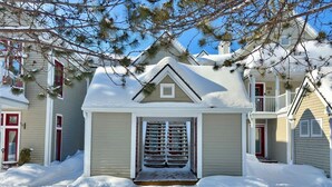 Een woonhuis met een sneeuwbedekte ingang, een klein portaal en een rode deur.