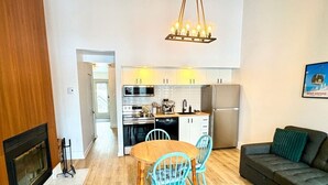 Een moderne keuken met witte kasten, een eettafel met stoelen, een bank en een open haard.