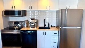 Een moderne keuken met roestvrijstalen apparatuur, witte kasten en een houten aanrecht.