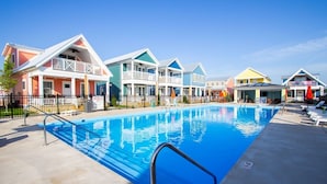 Una piscina con una escalera metálica, rodeada de casas coloridas con balcones.