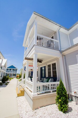 A two-story house with a balcony, a porch, and a small garden area.