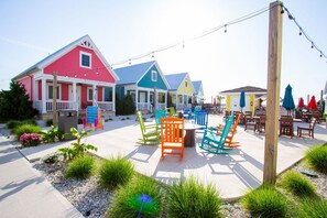 A colorful building with a porch, outdoor seating, and a clear sky. - Coastal Charm: 2 Bed/1.5 Bath Lakeside Cottage! (Celina)
