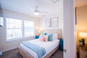 A bedroom with a bed, a ceiling fan, a window, and a nightstand with a lamp. - Coastal Charm: 2 Bed/1.5 Bath Lakeside Cottage! (Celina)