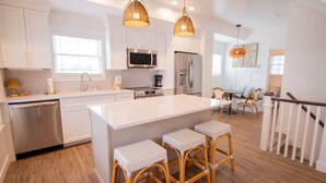 A modern kitchen with white cabinets, stainless steel appliances, and a large island with bar stools.