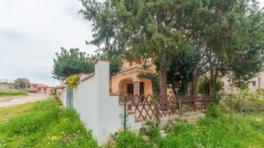 A building with a white exterior, a brown fence, and a tree in front. - Vacation Home 'Villa Marisol Agrustos' with Private Terrace, Wi-Fi and Air Conditioning (Budoni)