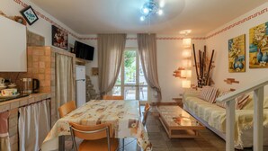 A dining area with a table and chairs, a kitchen with a stove, a sofa, and a staircase. - Vacation Home 'Villa Marisol Agrustos' with Private Terrace, Wi-Fi and Air Conditioning (Budoni)