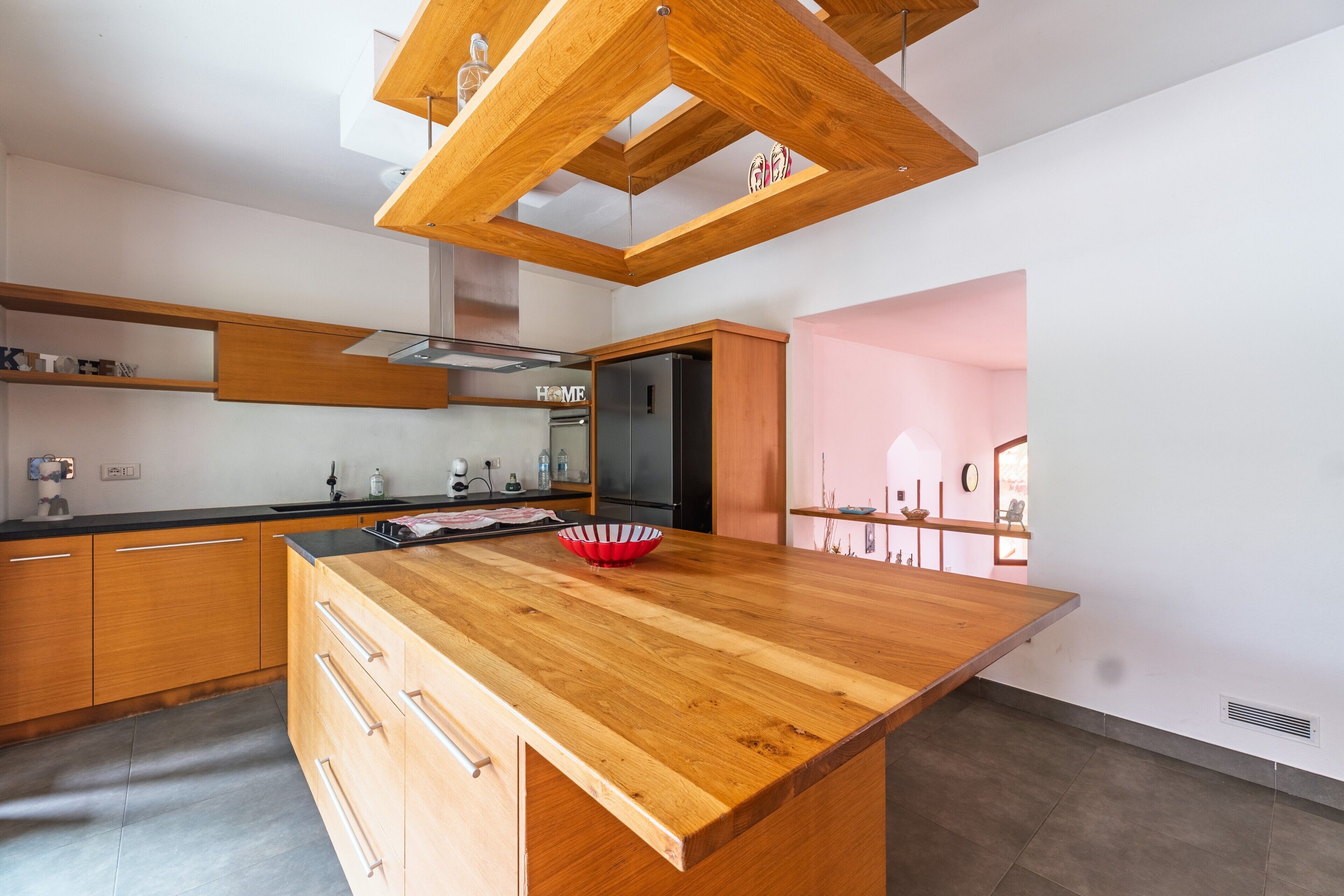 A modern kitchen with wooden cabinetry, a central island, and a built-in oven.
