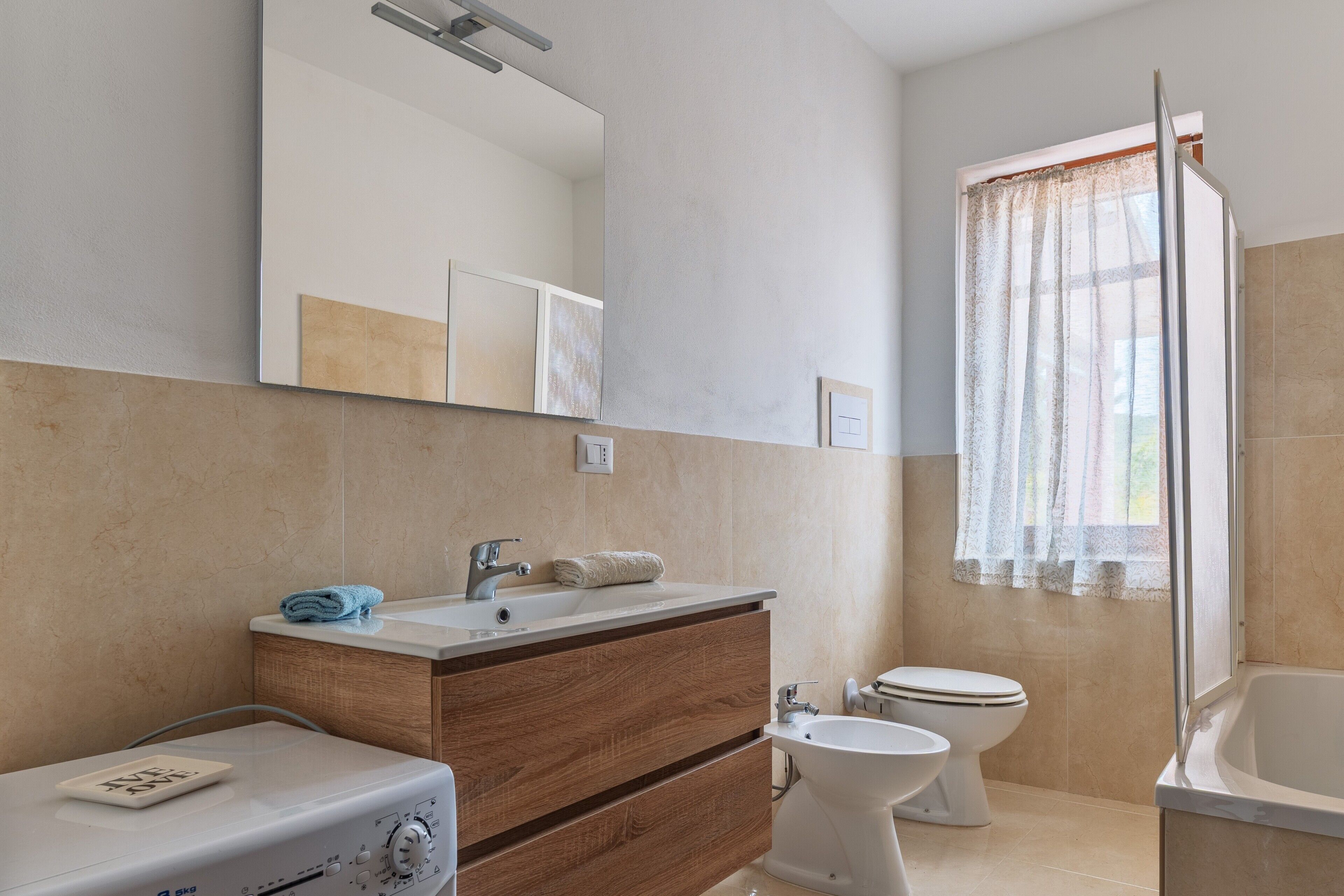 A bathroom with a sink, mirror, toilet, bidet, and bathtub.