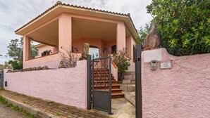 Ein pinkfarbenes Gebäude mit überdachter Eingangspartei und einer Treppe, mit einem Schild mit der Nummer 15.