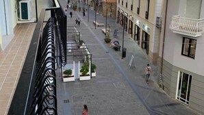 Una calle peatonal flanqueada por edificios, cielo despejado y algunas personas caminando.