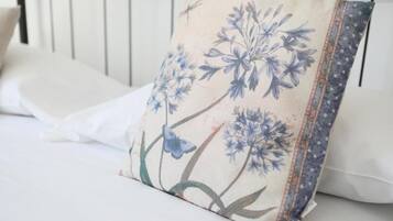 Un cuscino con un motivo floreale su un letto con biancheria bianca.