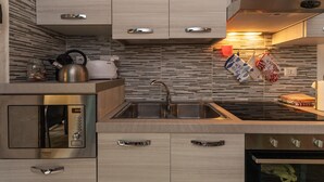 Una cucina moderna con forno a microonde integrato, lavello in acciaio inossidabile e piano cottura.