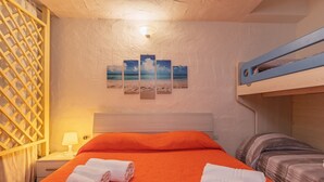 Una stanza con un letto, un letto a castello, un comodino con una lampada e decorazioni murali.