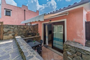 Un patio con suelo de piedra, una mesa con sillas y un muro de piedra.