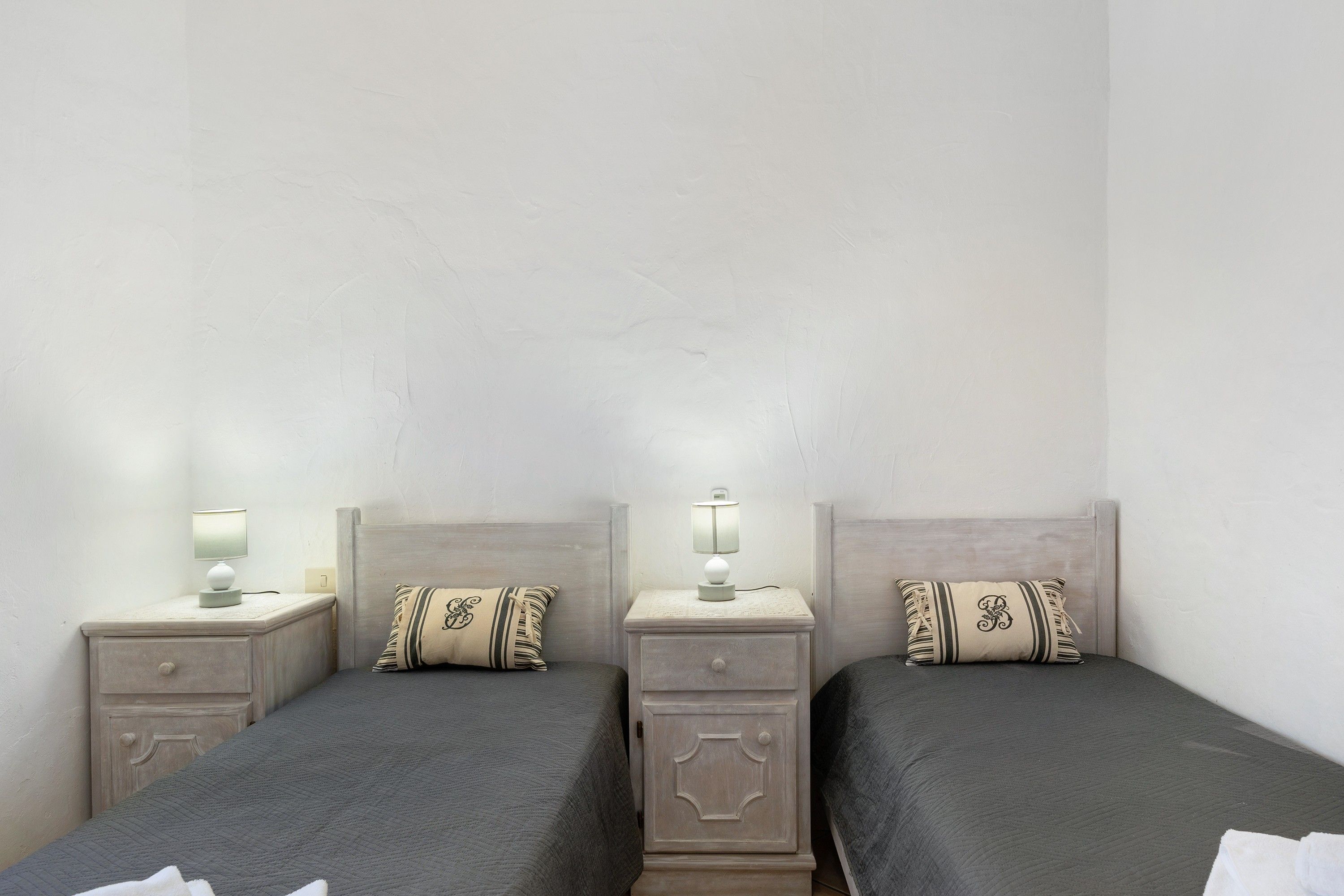 Una habitación de hotel con dos camas, cada una con una mesita de noche y una lámpara.