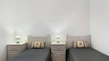 Una habitación de hotel con dos camas, cada una con una mesita de noche y una lámpara.