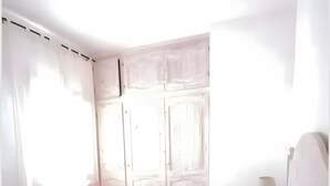 Ein Schlafzimmer mit Bett, Vorhängen, einem Nachttisch und einer Lampe.