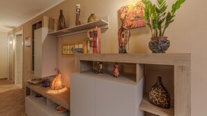 A hallway with shelves displaying various decorative items, a potted plant, and a lit lamp.