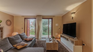 A living room with a sofa, coffee table, TV, and a sliding glass door leading to an outdoor area.
