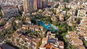 A densely packed urban area with residential buildings, a large swimming pool complex, and high-rise buildings in the background. - Sea&Sun Premium Apartamento (Torrevieja)
