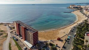 A coastal hotel with a beach view, a parking lot, and a road leading to the beach. - Sea&Sun Premium Apartamento (Torrevieja)