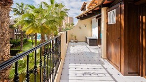 A balcony with a tiled floor, a wooden door, and a view of palm trees and a building in the background. - Sea&Sun Premium Apartamento (Torrevieja)