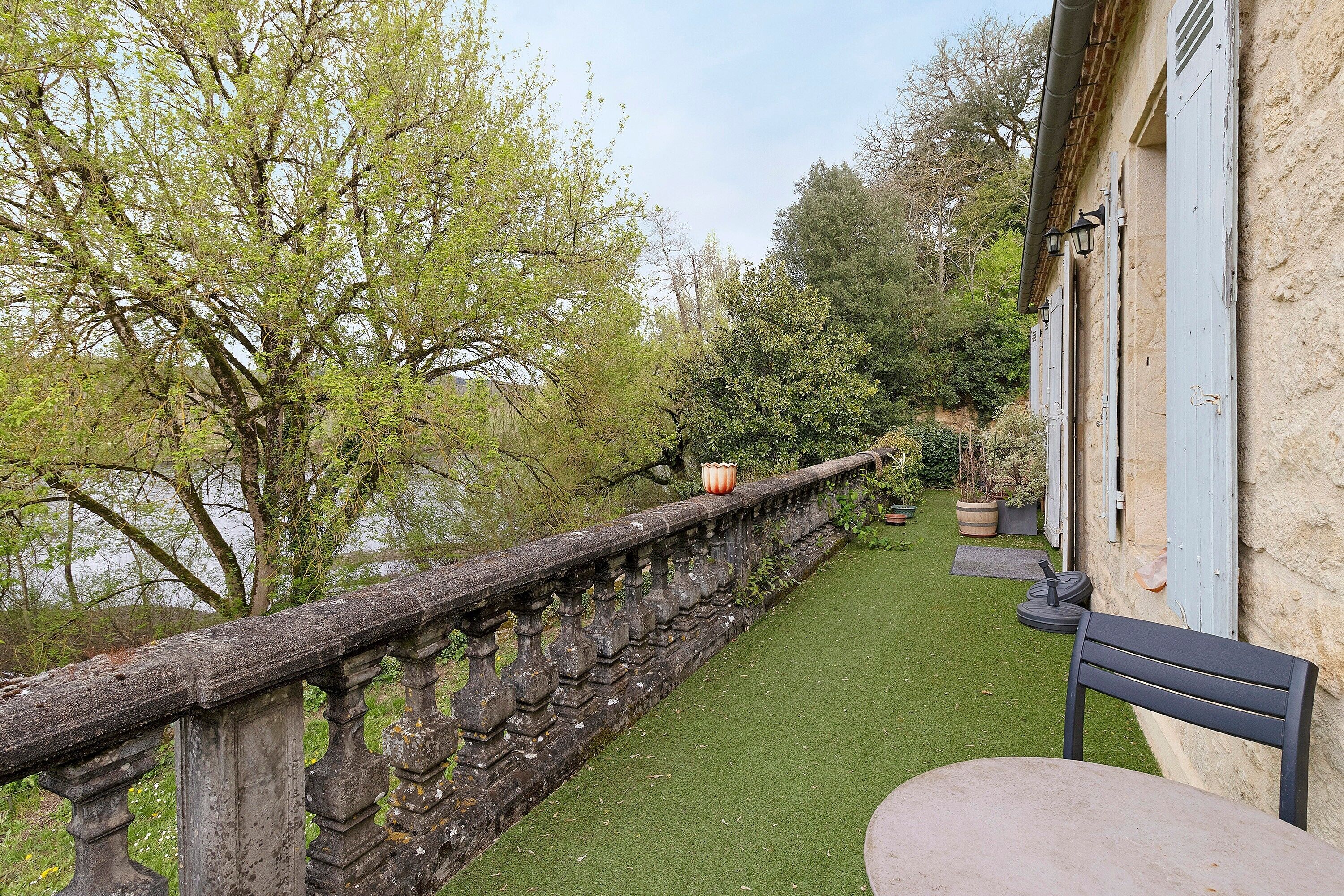 A stone balustrade, a bench, and a building with blue shutters.